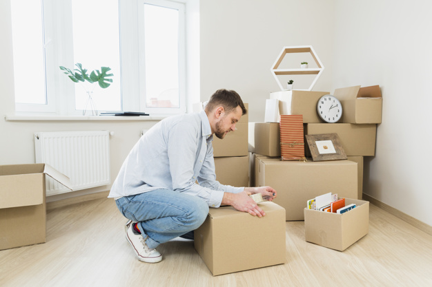 young-man-packing-cardboard-boxes-home_23-2148059989